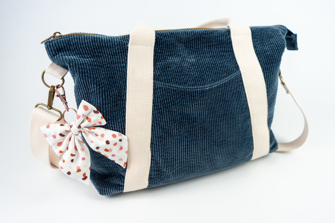 Blue corduroy bag with a white bow featuring pink dots on a white background
