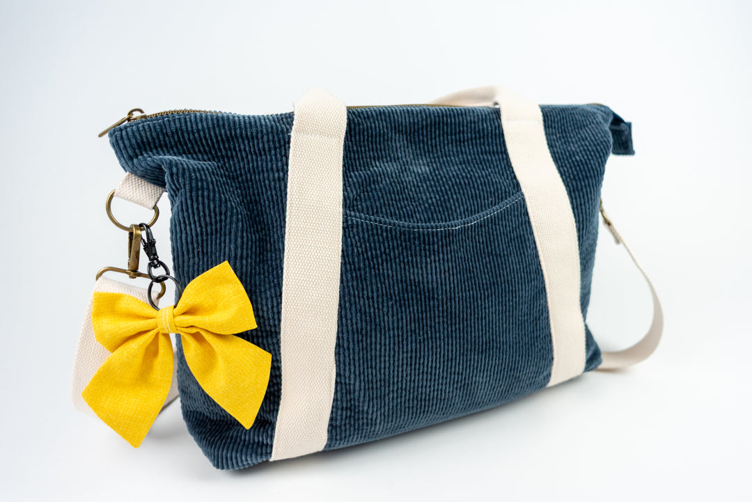 Blue corduroy bag with a yellow bow on a white background