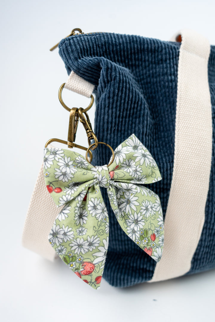 Blue corduroy bag with a floral bow keychain on a white background