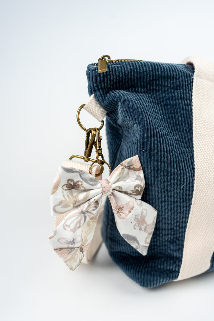 Blue and white striped fabric pouch with a bow keychain with butterflies on a white background