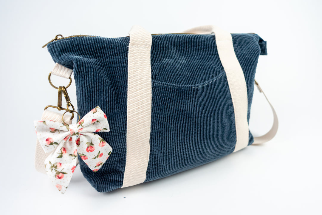 Blue corduroy bag with a floral keychain on a white background