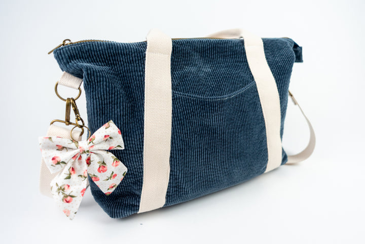 Blue corduroy bag with a floral keychain on a white background
