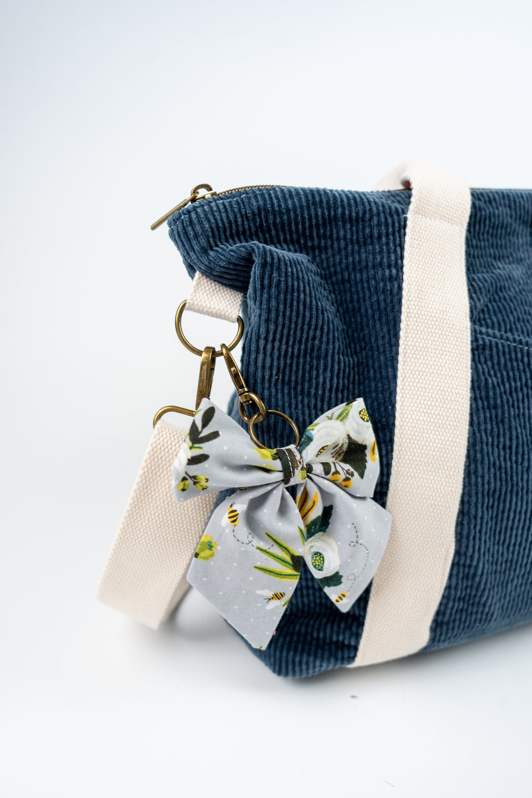 Blue corduroy bag with a floral bow keychain on a white background