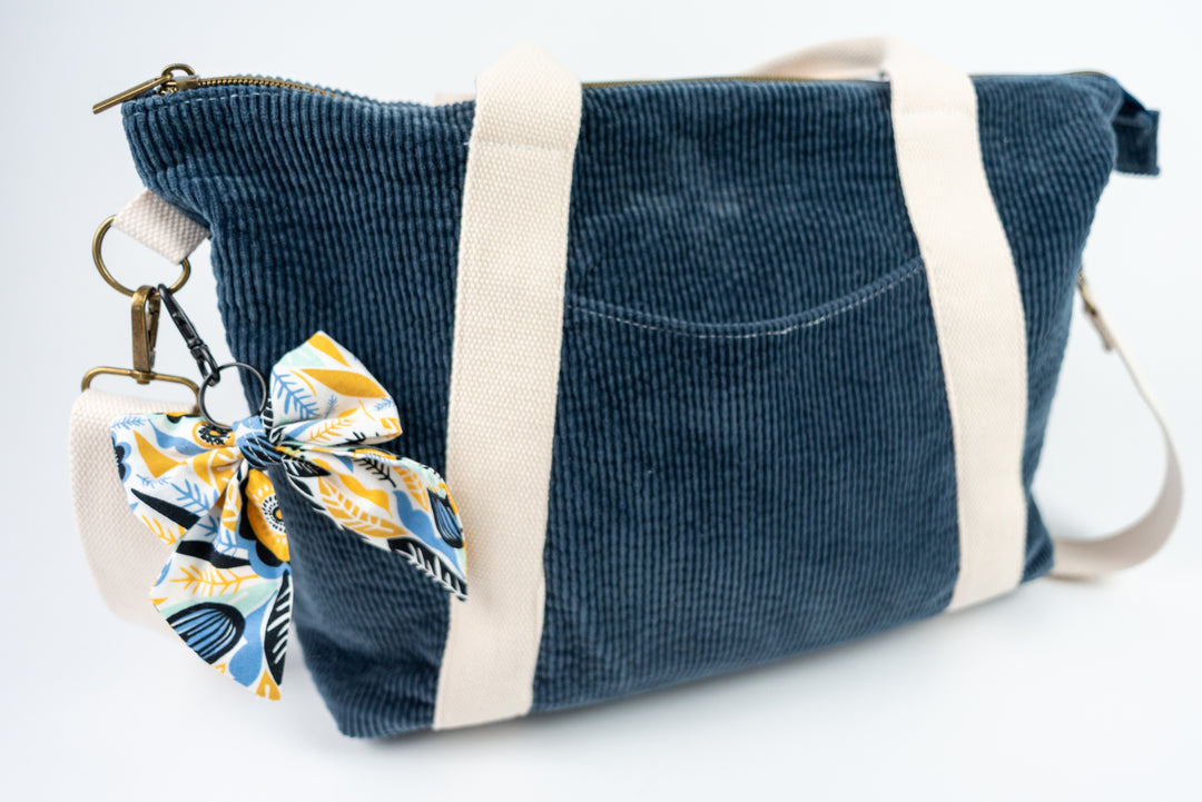 Blue corduroy bag with a floral keychain on a white background