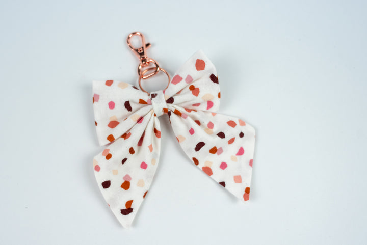 White bow keychain with colorful polka dot pattern on a white background