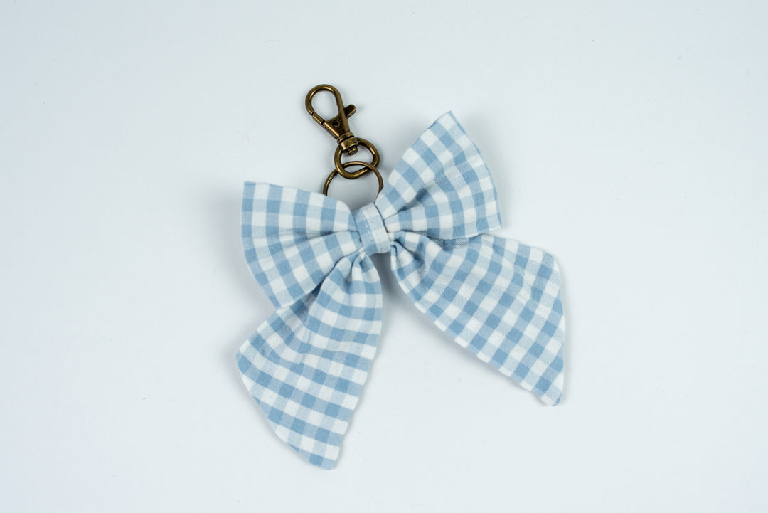 Blue and white checkered bow keychain on a light gray background