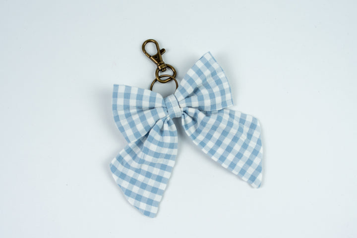 Blue and white checkered bow keychain on a light gray background