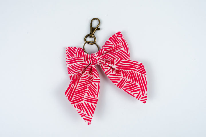 Pink and white patterned bow keychain on a white background