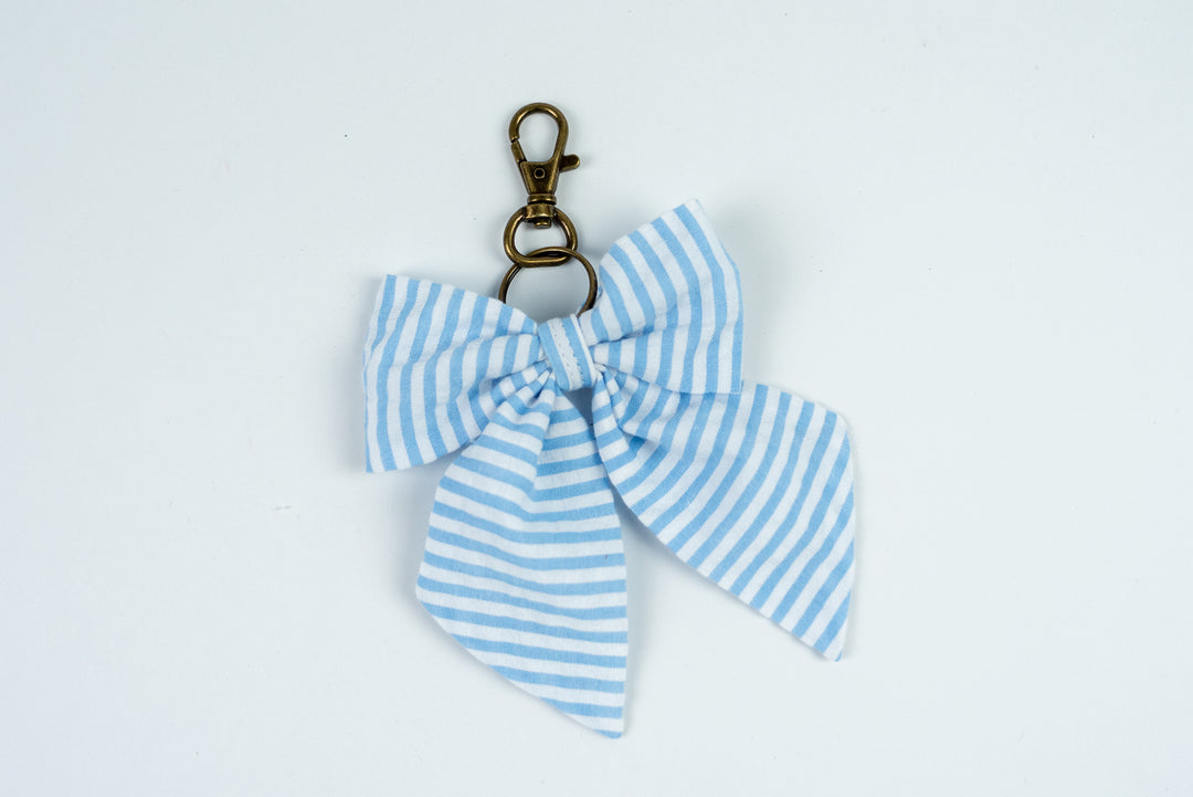 Blue and white striped bow keychain on a light gray background