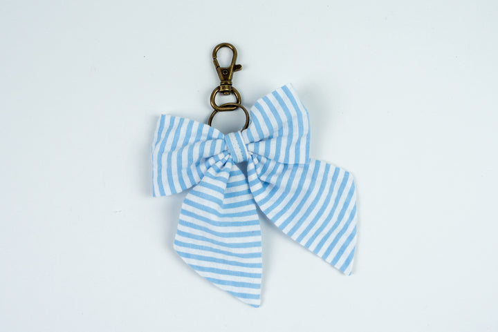 Blue and white striped bow keychain on a light gray background