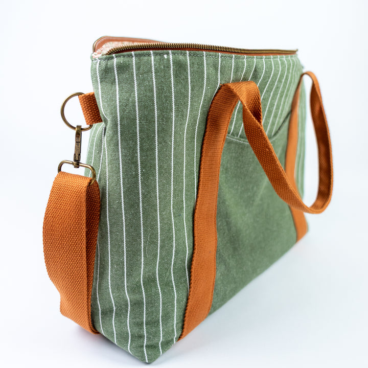 Green striped bag with brown handles and strap on a white background