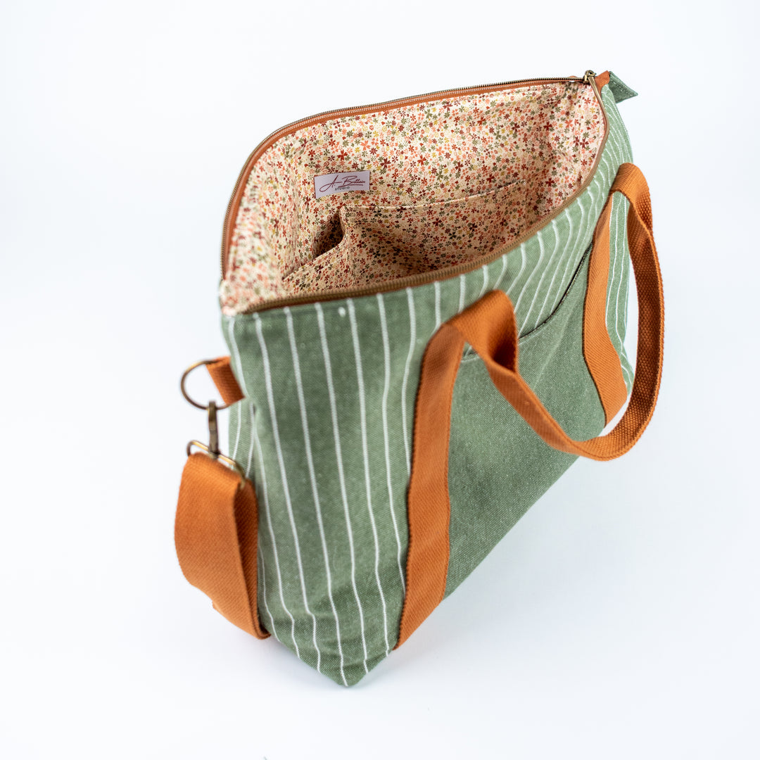 Green striped bag with brown straps on a white background