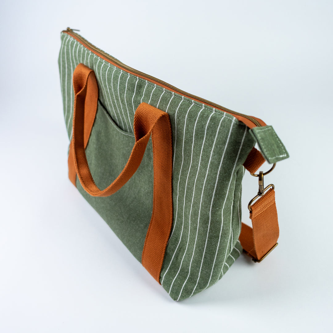 Green striped bag with brown handles and strap on a white background