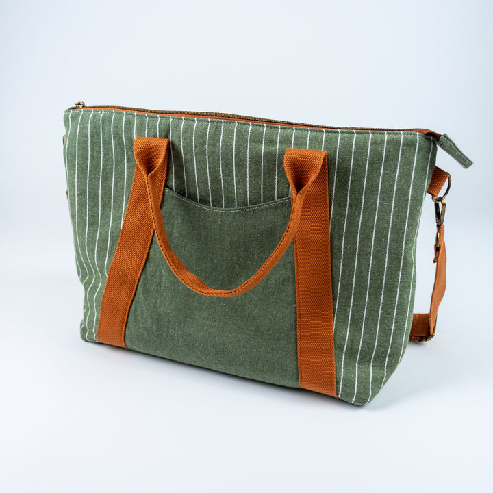 Green striped tote bag with brown handles and strap on a white background