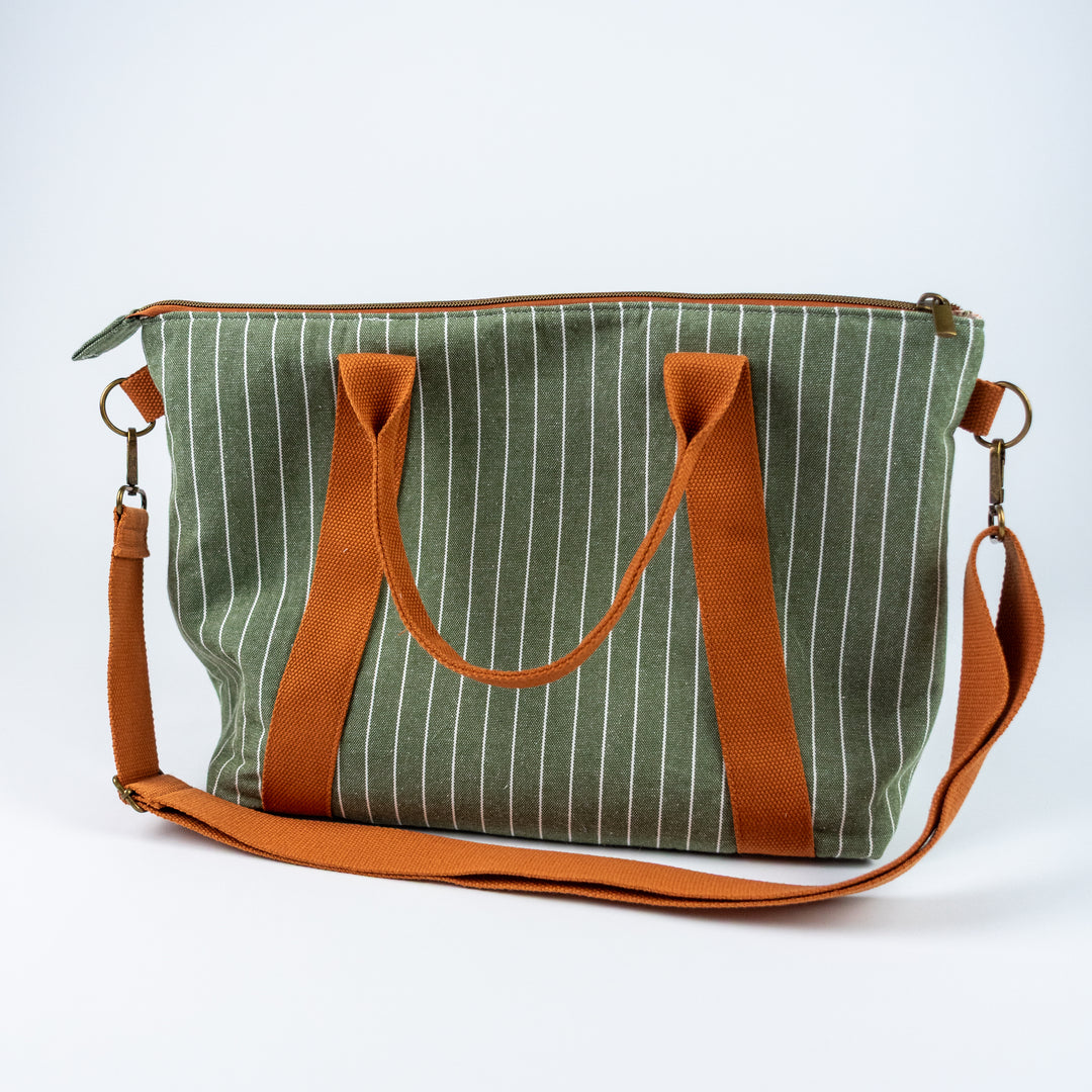Green striped bag with brown handles and strap on a white background