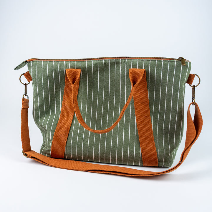Green striped bag with brown handles and strap on a white background